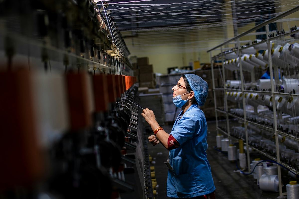 Textile factory operator checking threads on a spinning machine